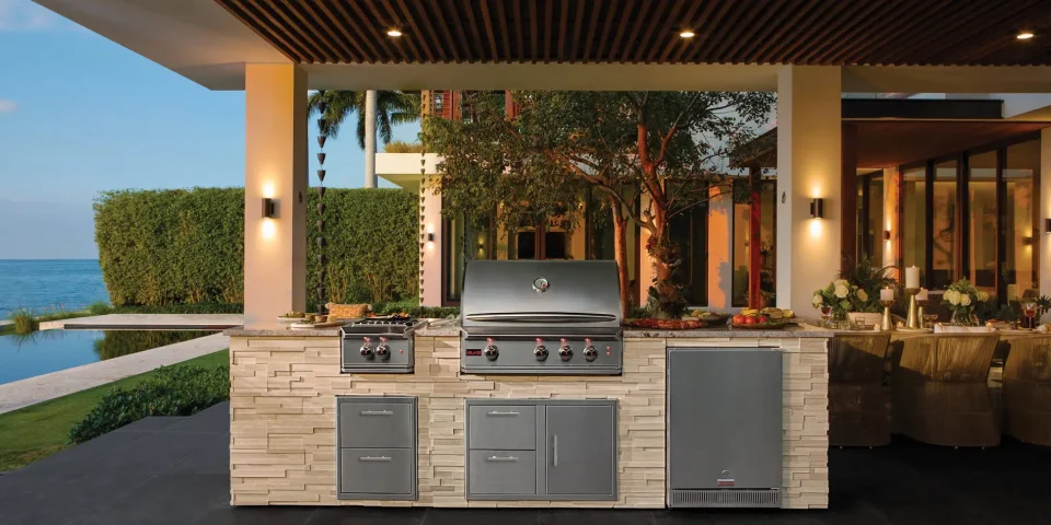 Luxury outdoor kitchen with Blaze Grills, featuring built-in gas grill, side burner, storage drawers, and outdoor fridge in a modern backyard cooking station