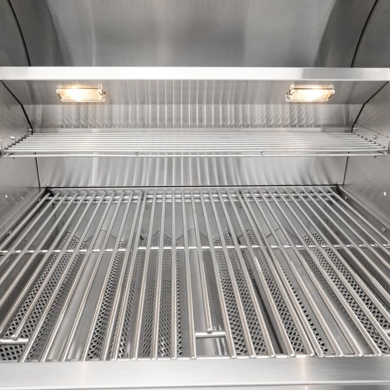 Interior view of a Coyote grill showing halogen lighting illuminating the cooking grates