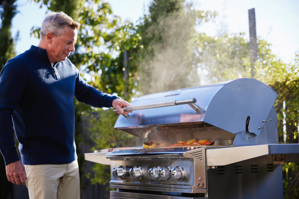 Man grilling outdoors using Blaze Outdoor Products freestanding LTE PRO gas grill in a backyard setting