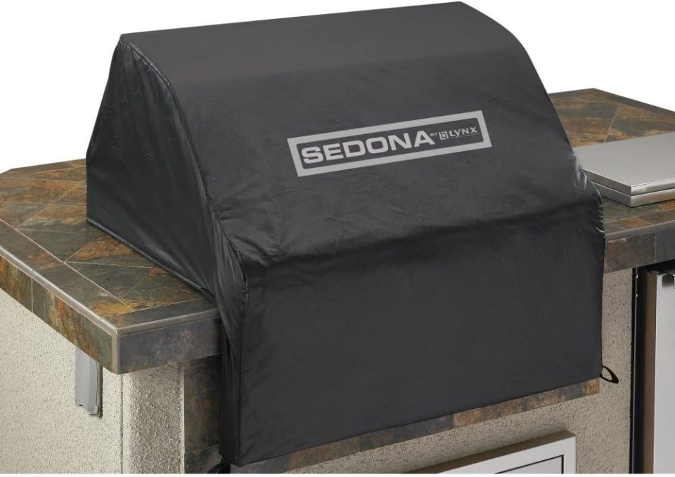 Built-in Lynx Sedona grill protected by a black vinyl cover on a tile BBQ island.