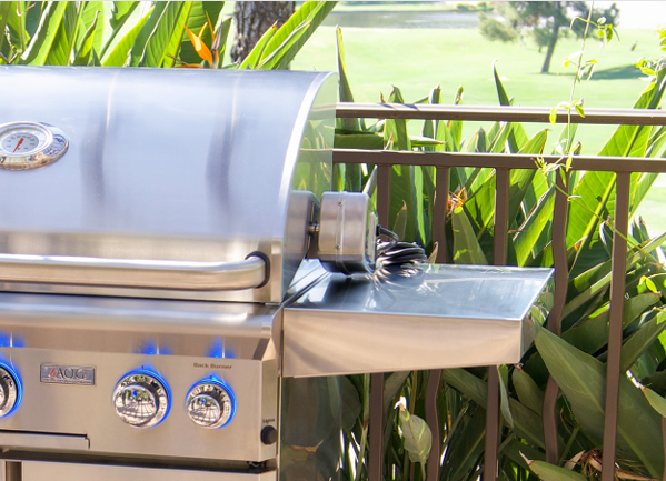 AOG T-Series Gas Grill with Blue LED Knobs on a Patio with Lush Greenery in the Background