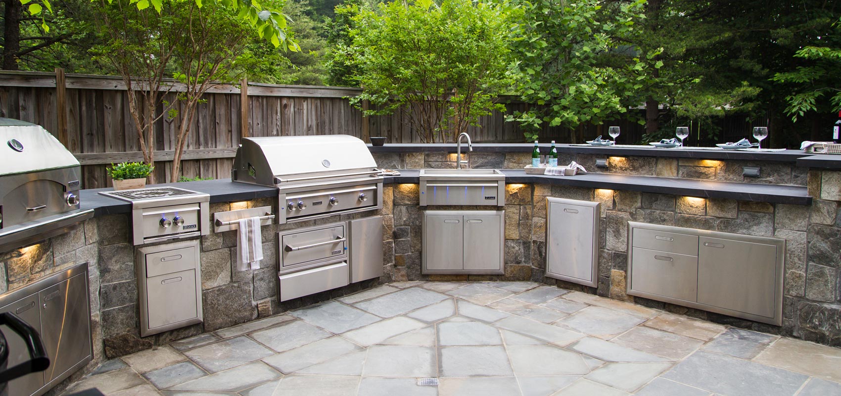 Lynx Grills built-in outdoor kitchen featuring stainless steel grill, side burner, sink, and storage drawers in a luxury patio setup