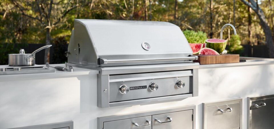Lynx Sedona built-in grill with stainless steel gas burners, outdoor sink, and storage drawers in a modern outdoor kitchen setting