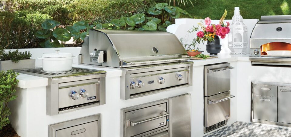 Lynx built-in outdoor kitchen with stainless steel grill, side burner, refrigerator, warming drawer, and grilling accessories in a luxury island layout.