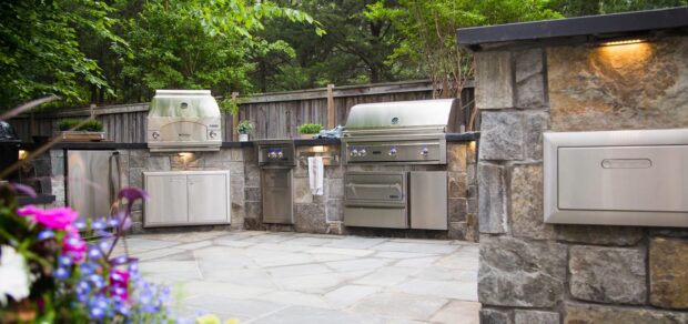 Lynx Outdoor Kitchen Products including built in grills, access doors, side burner, and drawers in a luxury stone island setup