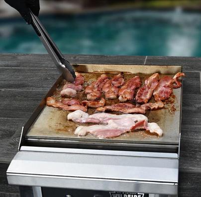 Cooking bacon on the Wildfire 15-Inch stainless steel built-in griddle—showcasing even heat distribution and premium design.