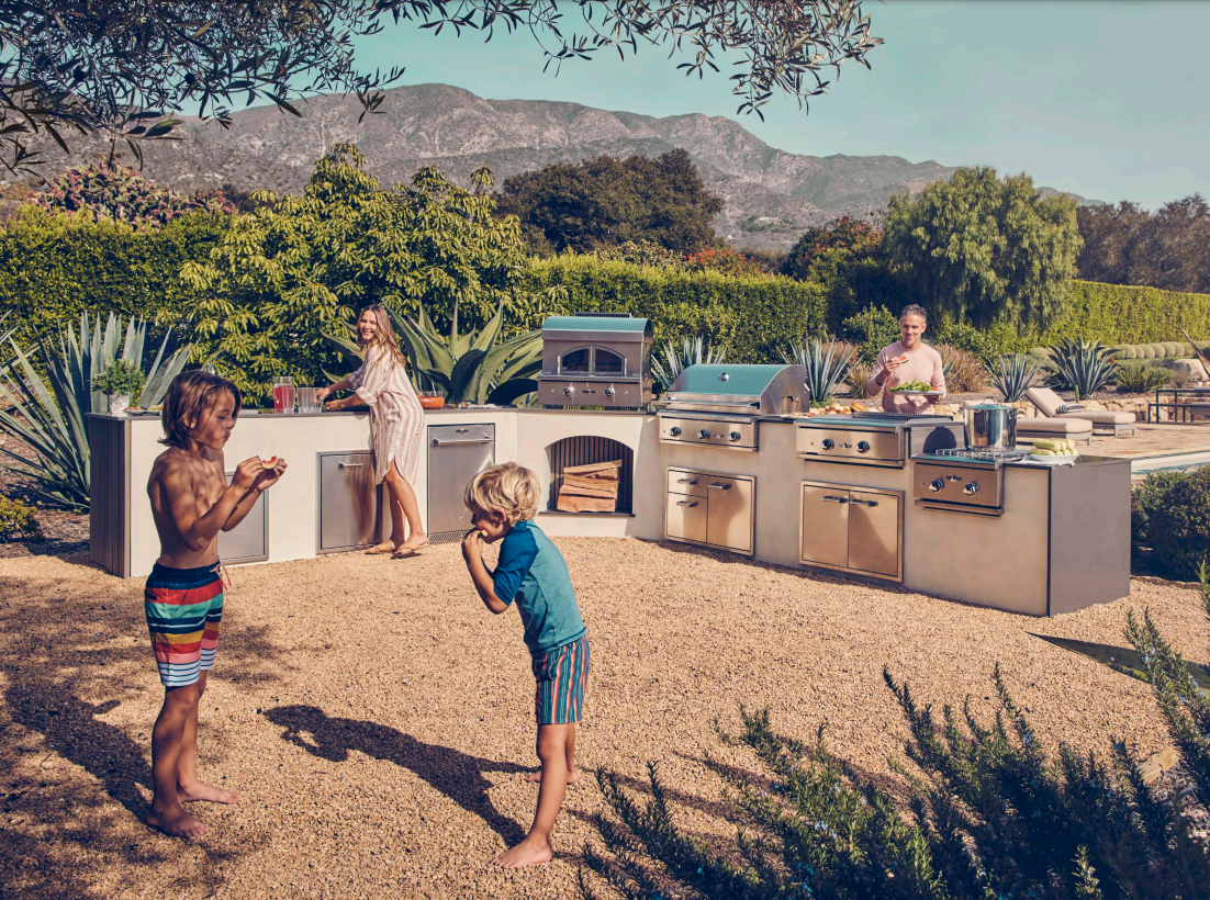 Delta Heat outdoor kitchen with built-in grills, pizza oven, and stainless steel storage in a scenic backyard