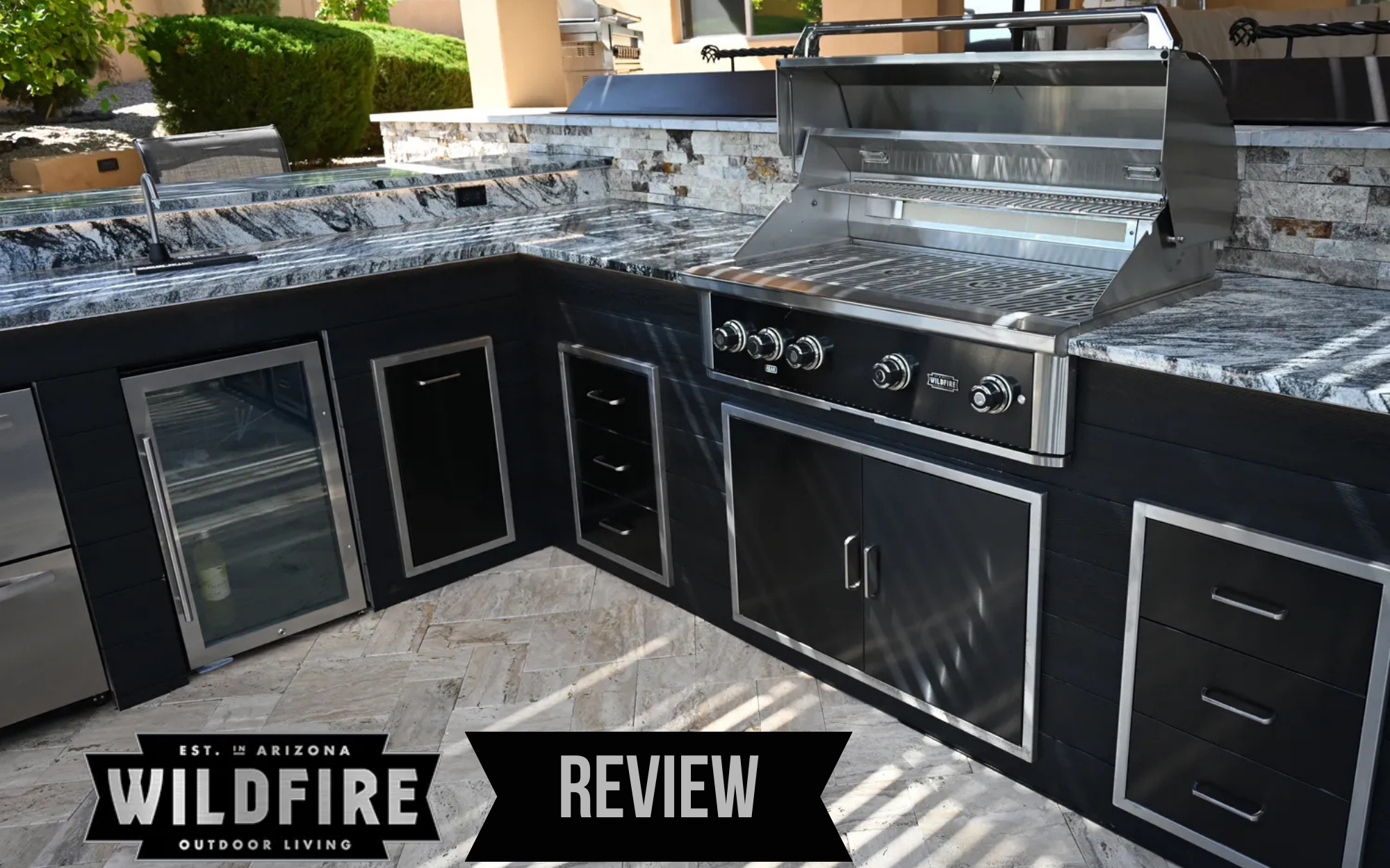 Wildfire Outdoor Living outdoor kitchen setup with stainless steel grill, storage drawers, and built-in refrigerator in luxury backyard