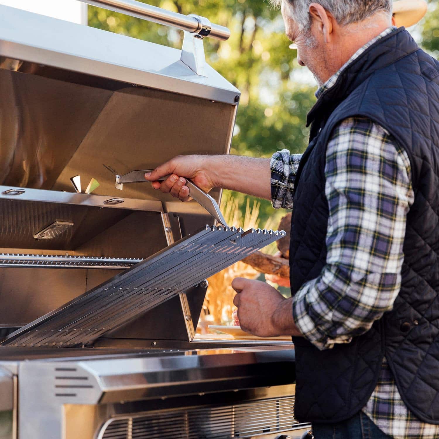 Man opening grate on Muscle 36-Inch Hybrid Grill