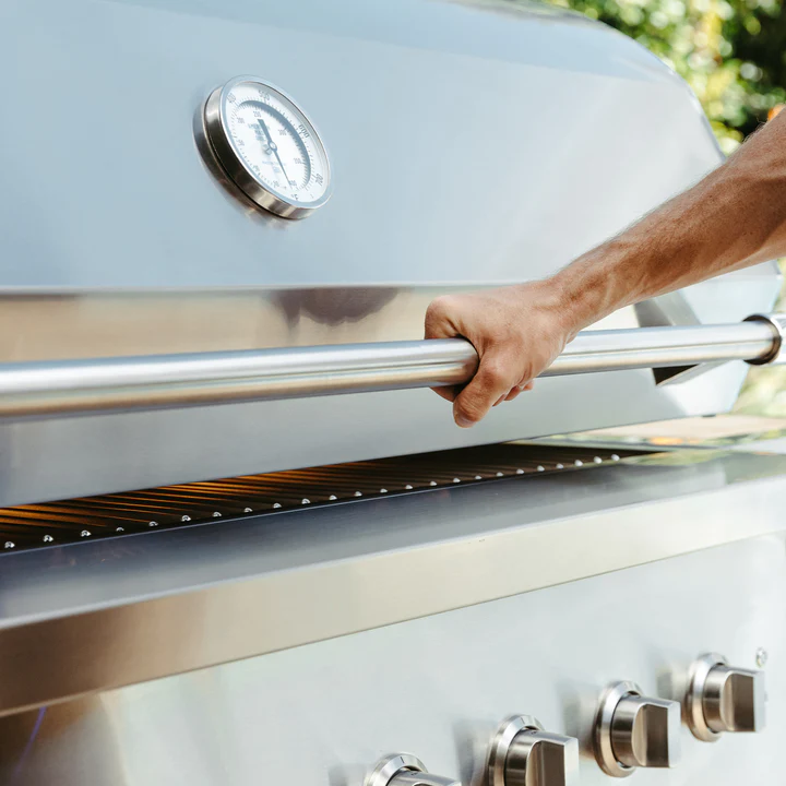Hand on handle of Encore 54-Inch Hybrid Grill